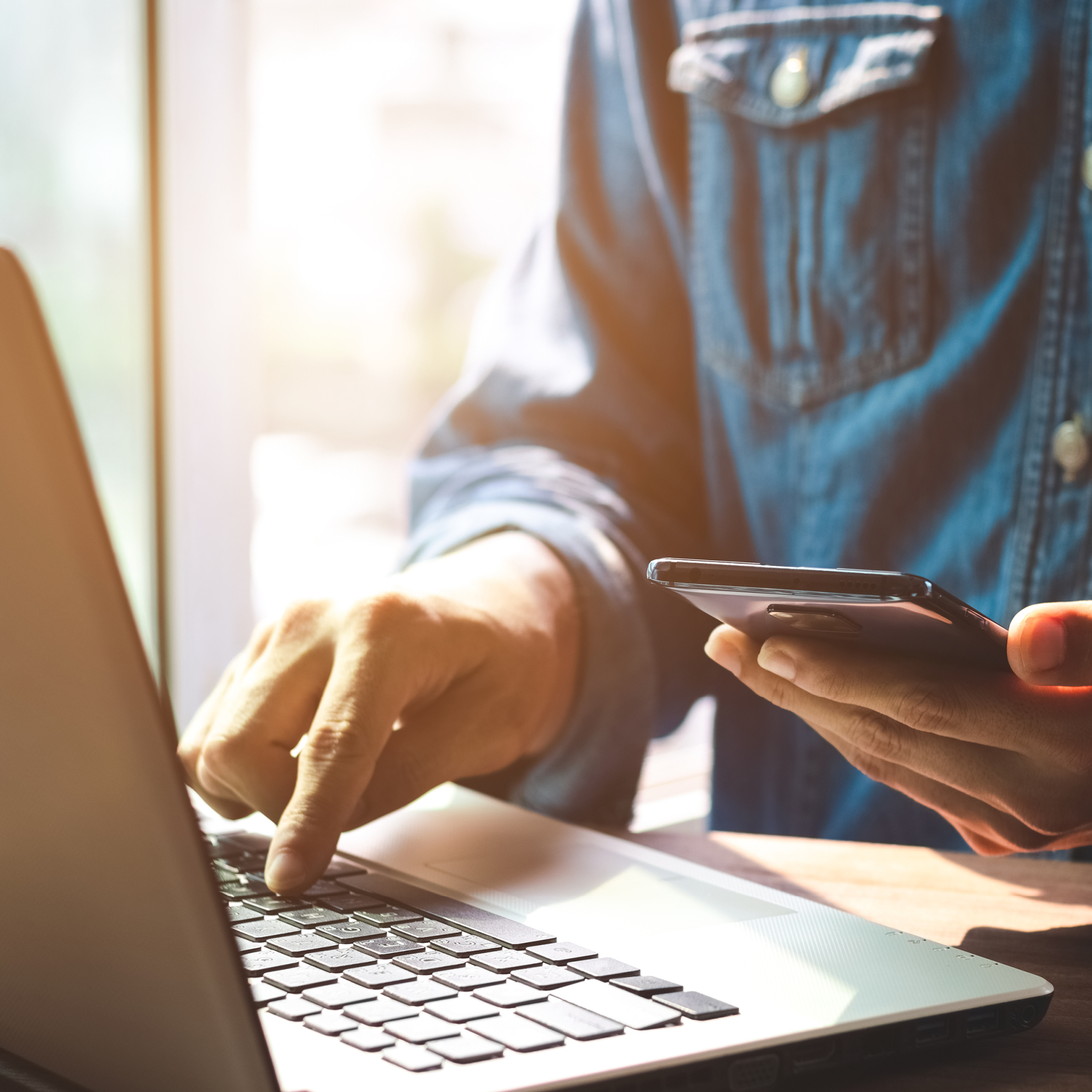 Person at laptop with phone