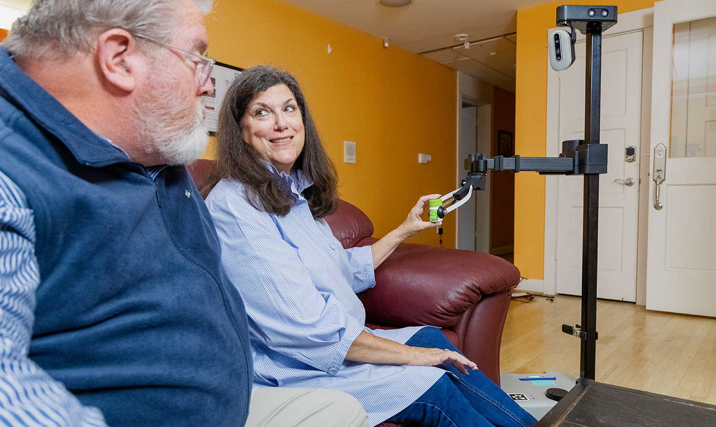 a robot helping as a home assistant by delivering a medication bottle to a woman